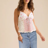 Woman wearing a floral sleeveless top and jeans on a beige background